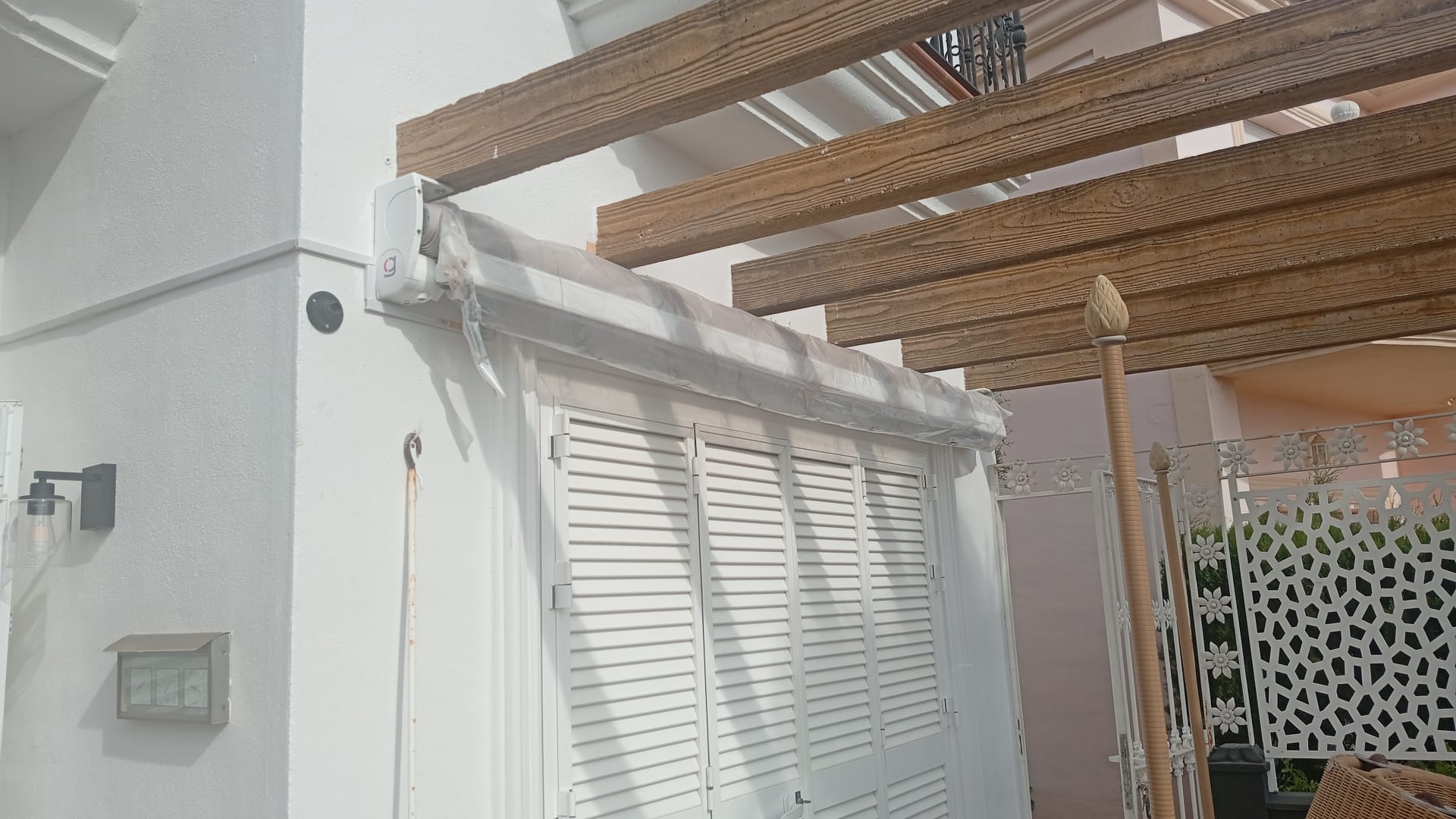 Toldo motorizado y pérgola con vigas de madera